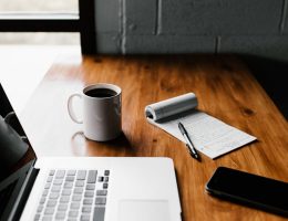 Escritorio con laptop, taza de café, cuaderno y pluma