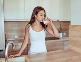 mujer bebiendo agua en casa como hábito para prevenir olor fuerte en la orina
