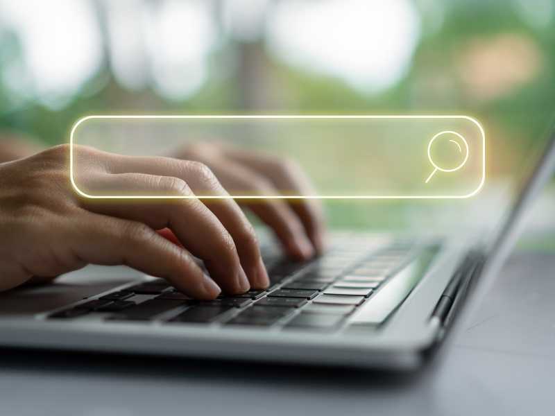 Persona escribiendo en una laptop con una barra de búsqueda iluminada, simbolizando la búsqueda de información confiable sobre salud y VIH.