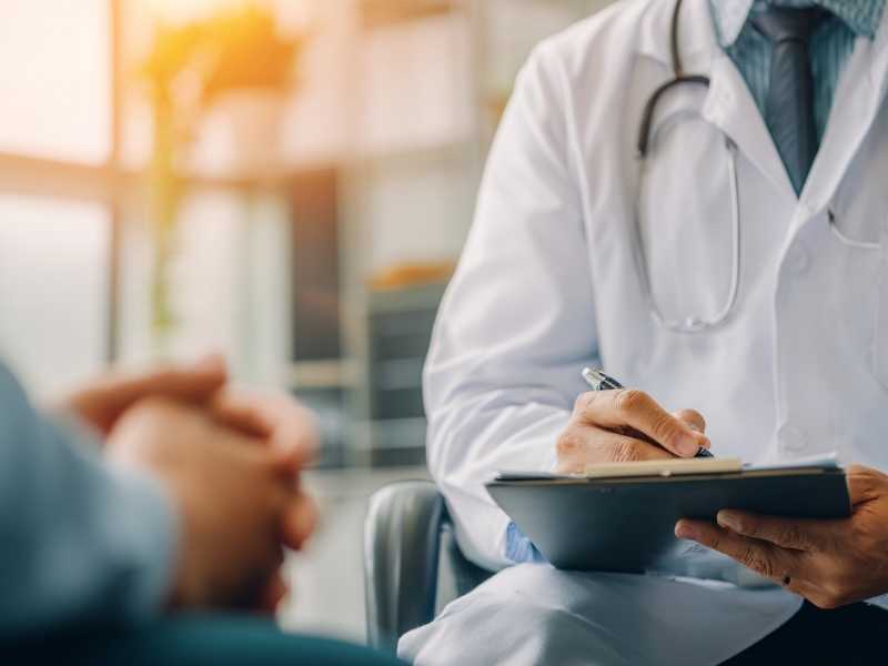 Médico tomando notas durante una consulta, representando el acompañamiento profesional para resolver dudas sobre el VIH y la salud sexual.